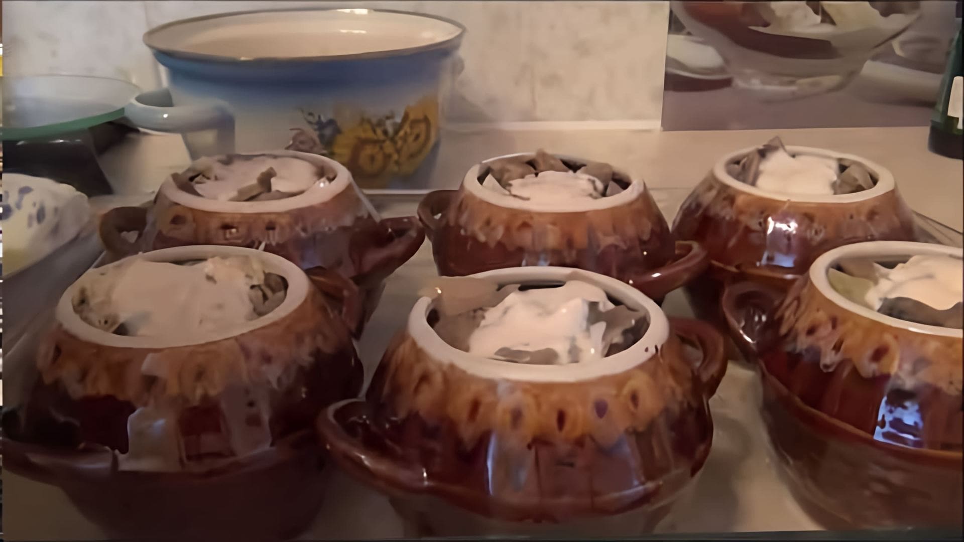 В этом видео демонстрируется процесс приготовления картофеля с грибами в горшочках