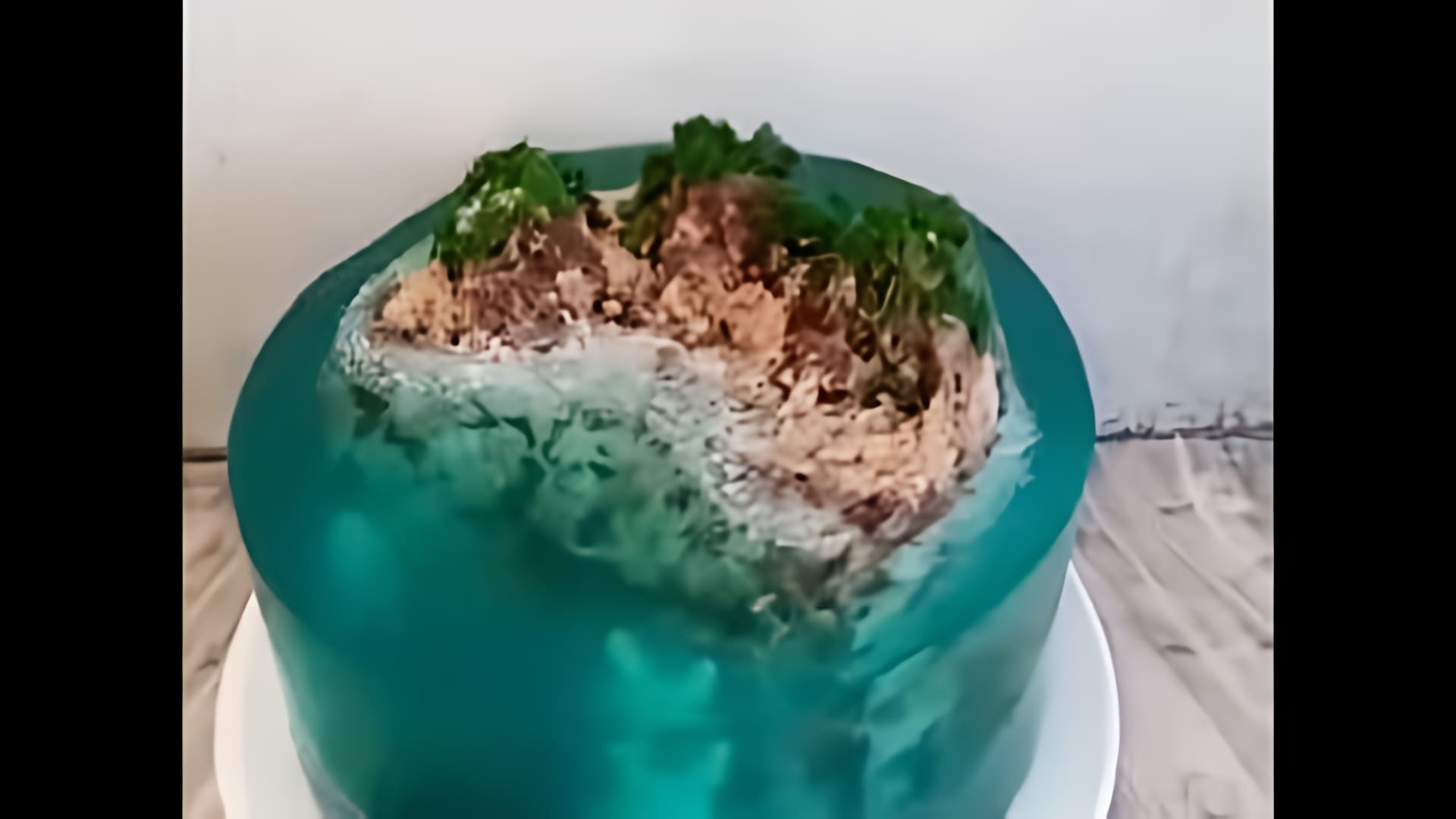 Видео-ролик с заголовком "Торт Остров с желе" представляет собой кулинарное шоу, в котором демонстрируется процесс приготовления оригинального десерта
