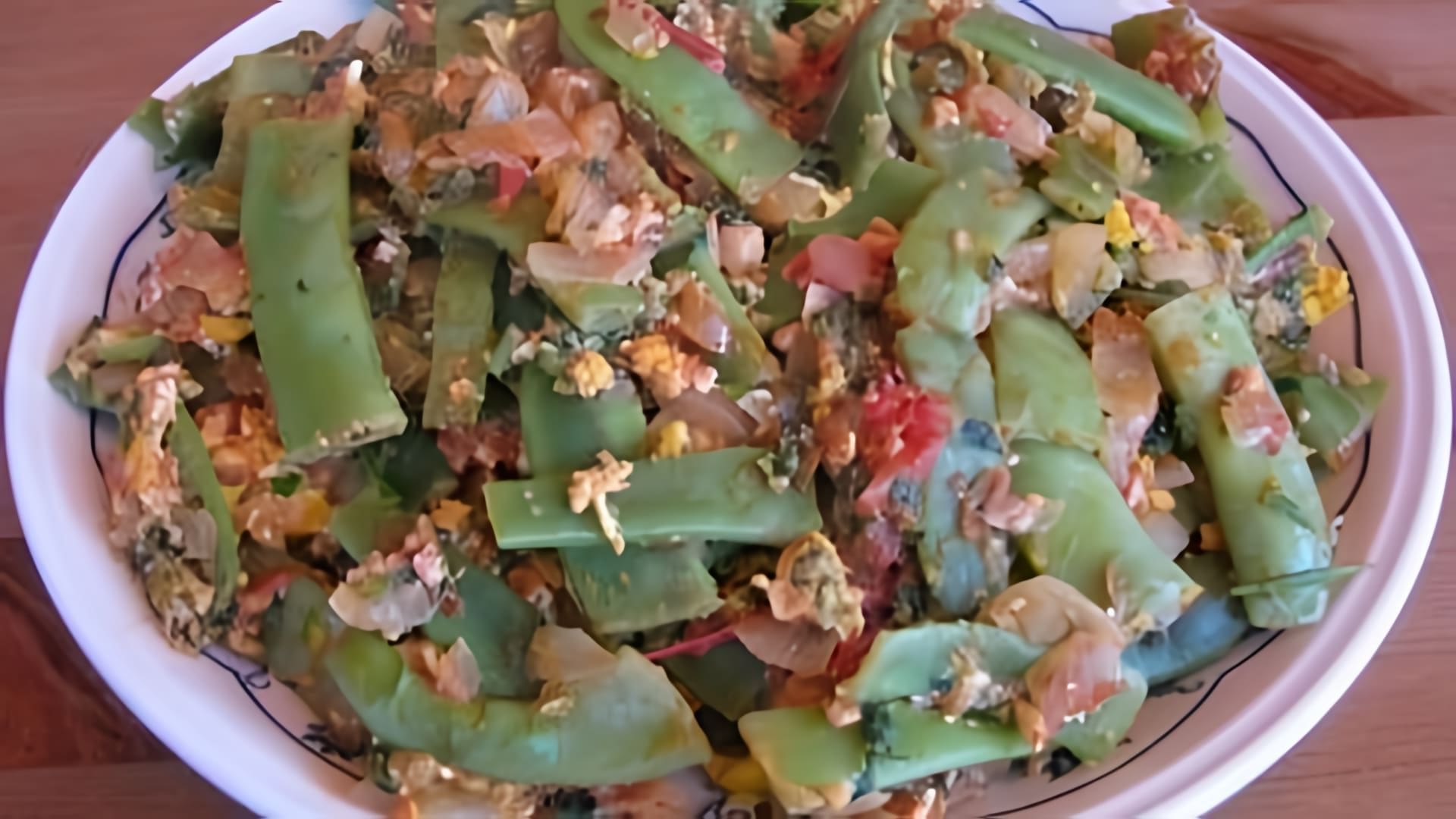 В этом видео демонстрируется процесс приготовления блюда из стручковой фасоли с помидорами и яйцом