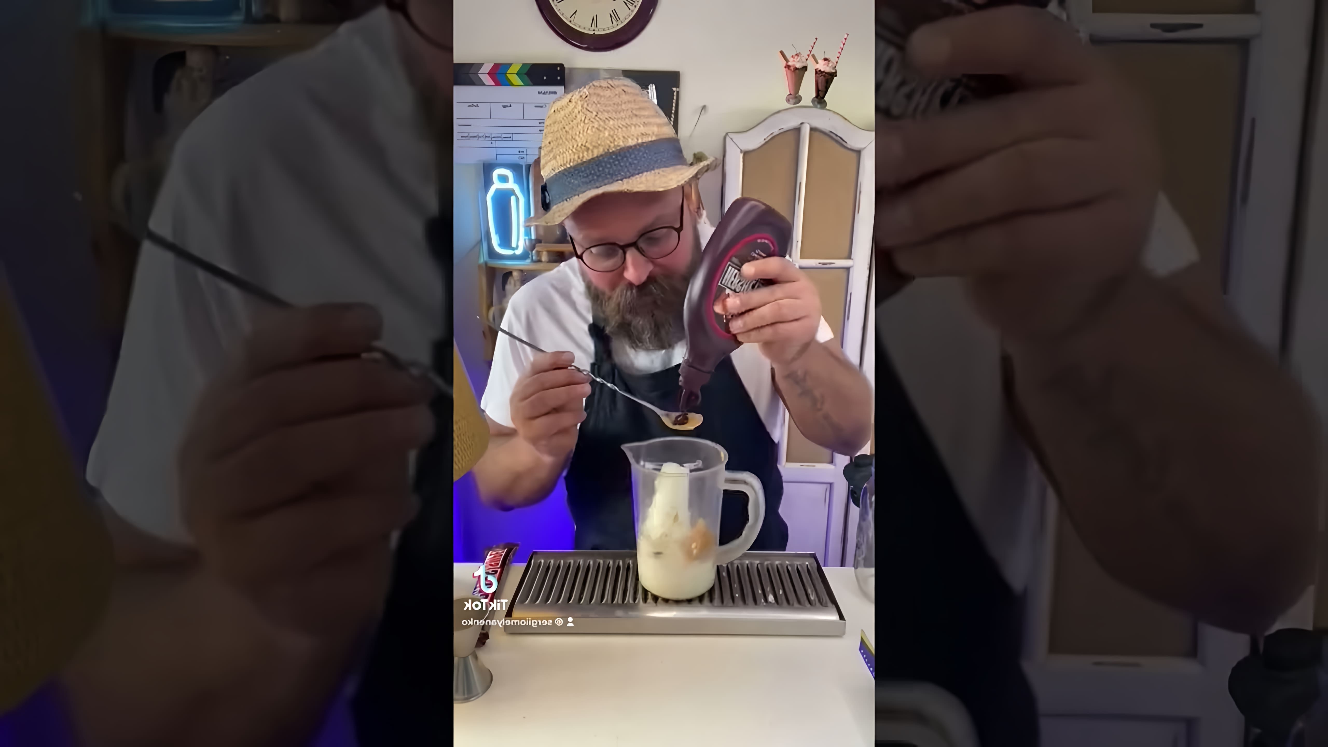 В этом видео демонстрируется процесс приготовления молочного коктейля с арахисовой пастой и шоколадными чипсами