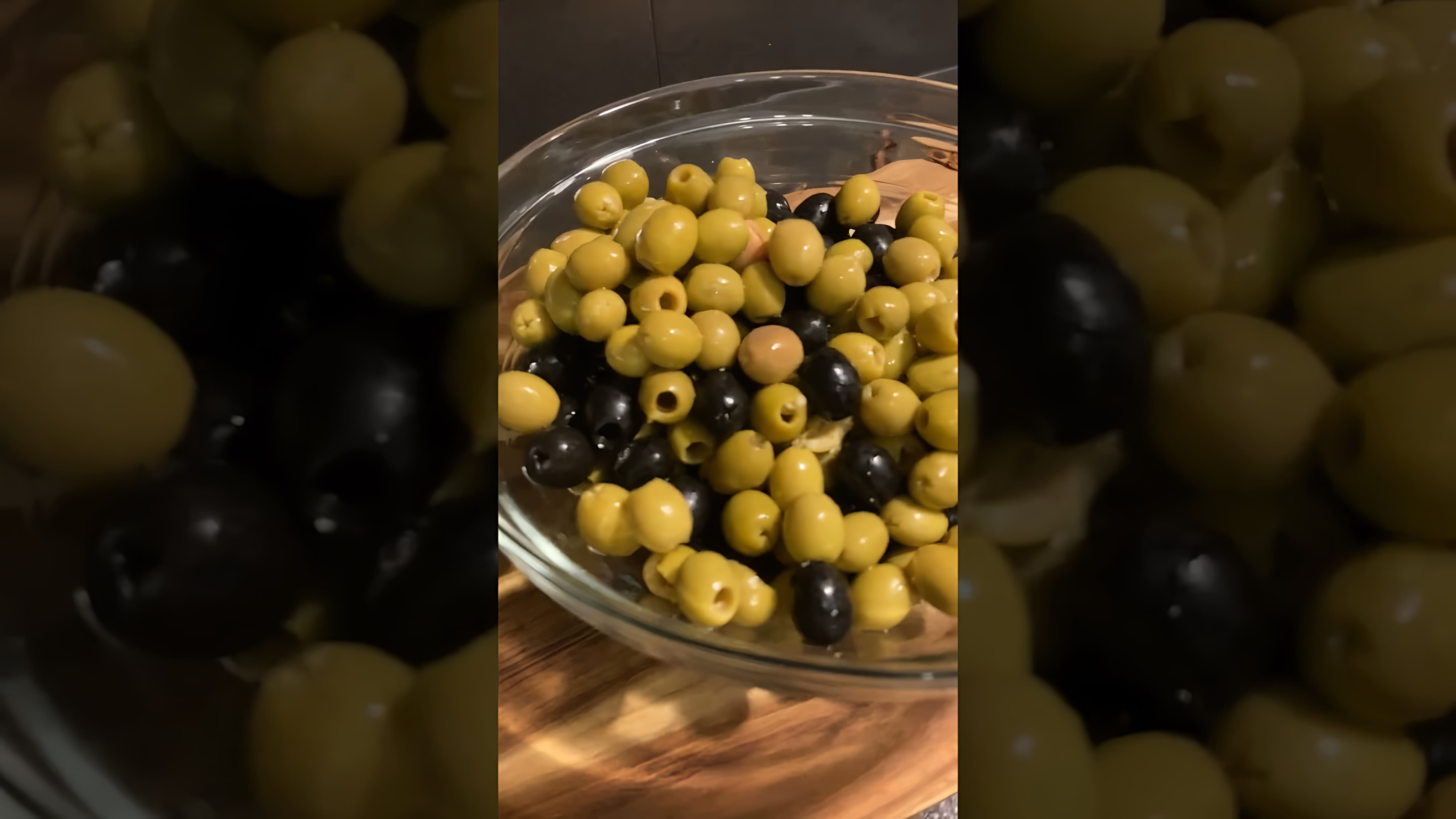 В этом видео демонстрируется процесс маринования зеленых и черных оливок с чесноком и зеленью